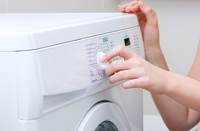 Hand som ställer in ett tvättprogram på en tvättmaskin